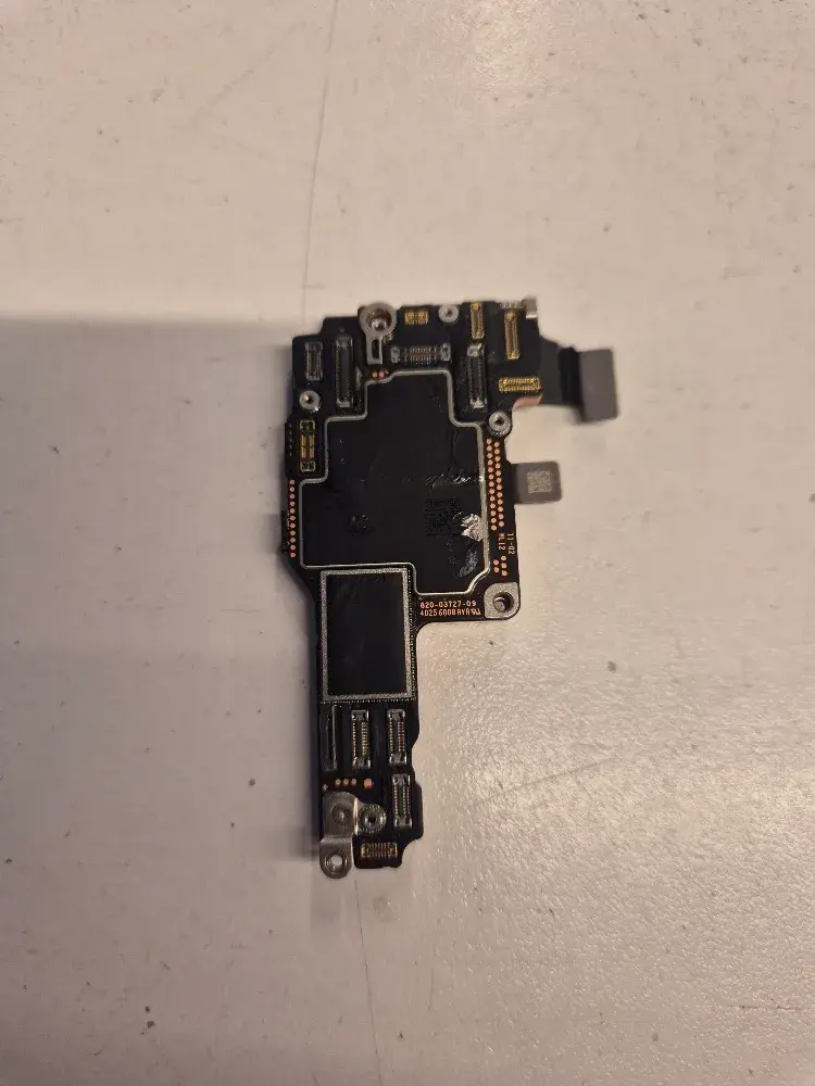 A stacked iPhone logic board removed from the phone, showing its connectors and the shielded chip area on one side