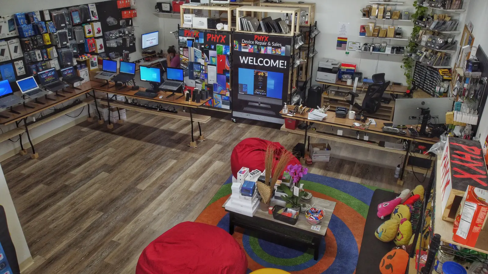 Inside the 95 Mill Street shop — laptops along the bench tables, accessory wall, and the WELCOME display