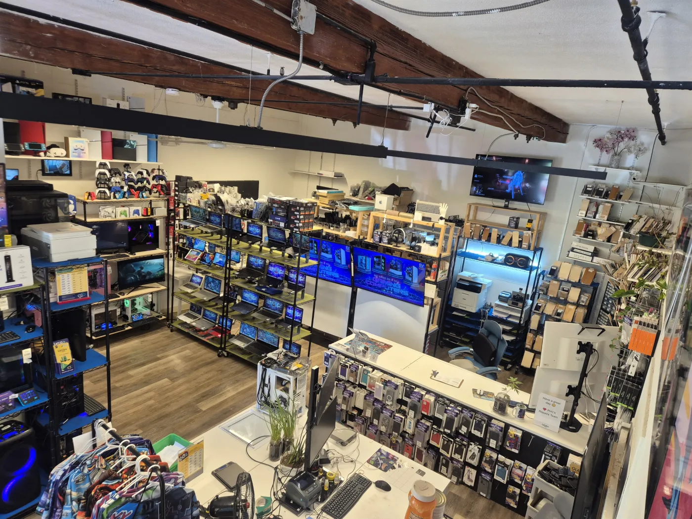 Wide view over the PHYX shop floor — repair counter, inventory racks and workbenches